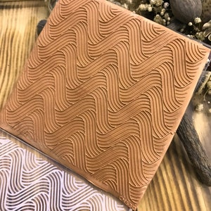 Pode incluir: Um carimbo de borracha marrom com um padrão ondulado. O carimbo está em uma superfície de madeira. O carimbo é etiquetado como "CNS30".