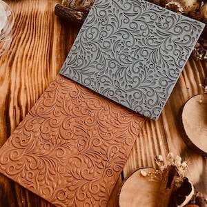 Op de afbeelding: Twee siliconen stempels met een decoratief bloemmotief. De bovenste stempel is grijs en de onderste stempel is bruin.