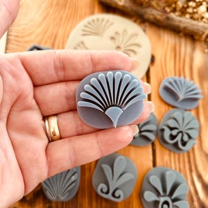 May include: A set of nine gray rubber stamps with different floral designs. The stamps are in various sizes and shapes, and they are all made of a soft, flexible rubber.
