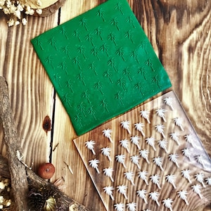 May include: Two palm tree patterned stamps, one green and one clear, on a wooden surface. The green stamp has a raised palm tree design, while the clear stamp has a white palm tree design.