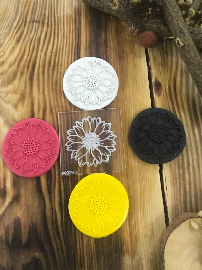 May include: Four round silicone stamps with a sunflower design. The stamps are white, red, black, and yellow.