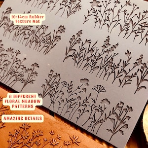 Puede incluir: Una estera de textura de goma gris con seis patrones diferentes de pradera floral. La estera mide 10-14 cm y tiene el texto "6 DIFFERENT FLORAL MEADOW PATTERNS" y "AMAZING DETAILS" impreso en ella.