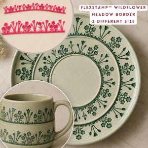 May include: Two pink flexible stamps labeled FLEXSTAMP WILDFLOWER MEADOW BORDER 2 DIFFERENT SIZE, shown with a light green ceramic plate and mug featuring a dark green embossed wildflower meadow border pattern around the edges.