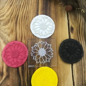 May include: Four silicone stamps with a sunflower design. The stamps are in red, black, white, and yellow.