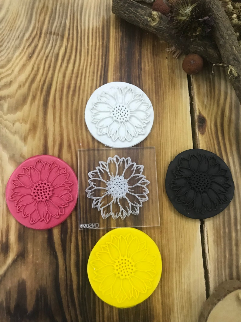 May include: Four silicone stamps with a sunflower design. The stamps are in red, black, white, and yellow.