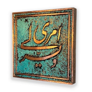 Op de afbeelding: Een vierkante koperen plaquette met een turquoise groene achtergrond. De plaquette heeft verhoogde koperen letters in Arabisch schrift. De letters zijn in een traditionele stijl en waarschijnlijk een naam of een zin.