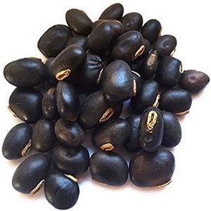 May include: A close-up of a pile of black beans. The beans are smooth and shiny, with a slightly oval shape.