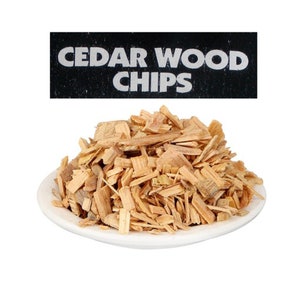 Könnte beinhalten: Ein weißer Keramikteller gefüllt mit Zedernholzspänen. Die Späne sind hellbraun und haben eine raue Textur. Ein schwarzes Etikett mit weißem Text lautet "CEDAR WOOD CHIPS".