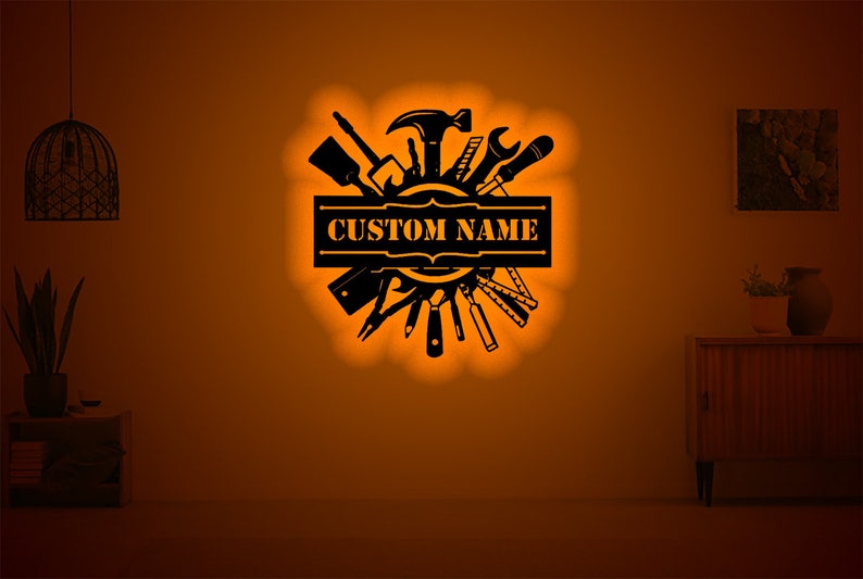 May include: Black metal wall art featuring a circle of tools with a banner that says "CUSTOM NAME".