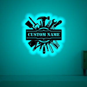 May include: Black silhouette of various tools arranged in a circle with a banner that says "CUSTOM NAME" in the center. The image is on a teal background.