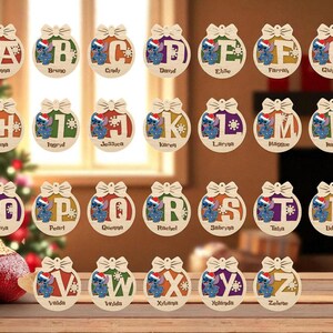 May include: Wooden Christmas ornaments with a bow design, each featuring a letter of the alphabet and a cartoon character wearing a Santa hat. The ornaments are in various colors and have names printed on them.