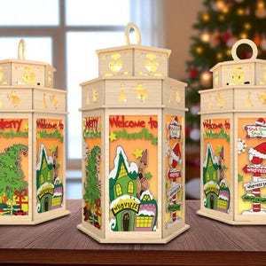 May include: Three wooden Christmas lanterns with cut-out designs and the words "Merry Christmas" and "Welcome to Whoville." Each lantern features a festive scene with a Christmas tree, houses, and signs. The lanterns have a handle on top.
