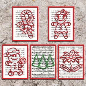 May include: Five framed Christmas-themed art pieces. The art includes red cut-out designs of a candy cane, gingerbread person, Santa, Christmas trees, and bells. Each piece is framed in a red border and set against a background of sheet music and holiday text.