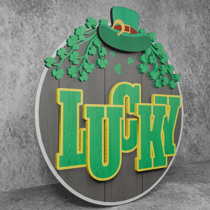 May include: A round wooden sign with a gray background and the word "LUCKY" in green letters with a yellow outline. The sign is decorated with green shamrocks and a green leprechaun hat with a gold buckle.