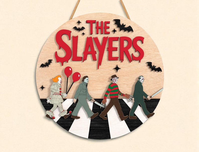 May include: Round wooden sign with the text "THE SLAYERS" in red, featuring horror movie characters walking on a black and white crosswalk. Includes bats and stars.