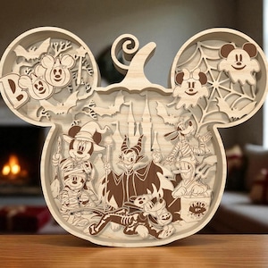 Puede incluir: Decoración de Halloween de madera con forma de calabaza con orejas de Mickey Mouse. El diseño presenta recortes en capas de personajes de Disney con disfraces de Halloween, murciélagos y la palabra "BOO".