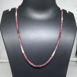 May include: A pink and white gemstone necklace with a graduated color pattern. The necklace is made of small, round beads and is approximately 18 inches long.