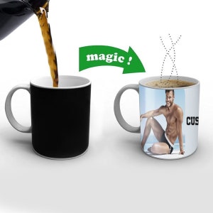 Könnte beinhalten: Eine schwarze Zauber-Tasse, die ein Farbbild eines Mannes in Badehose enthüllt, wenn man heiße Flüssigkeit hineingießt. Die Tasse trägt die Aufschrift "CUSTOMIZE YOUR MUG".