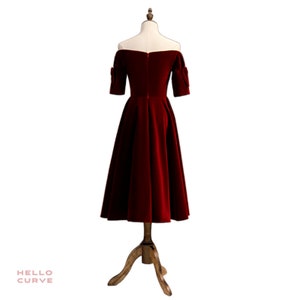 May include: A red off-the-shoulder velvet dress with short sleeves and a full skirt.