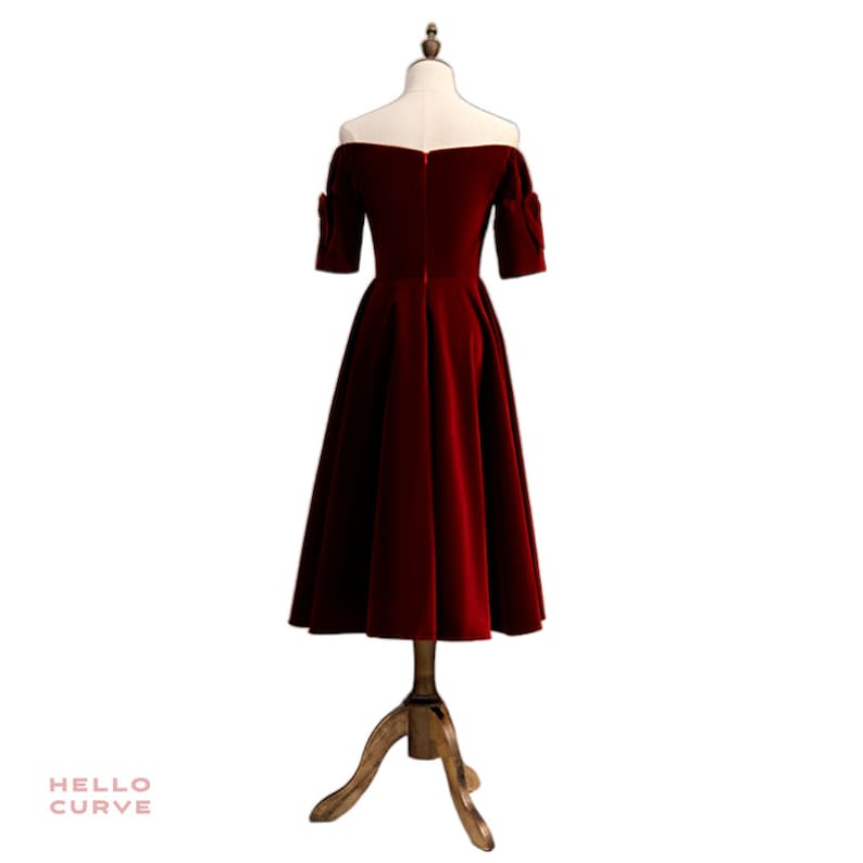 May include: A red off-the-shoulder velvet dress with short sleeves and a full skirt.