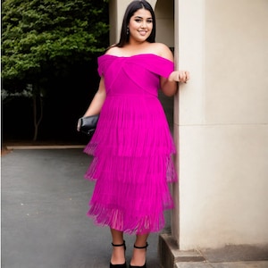 May include: A woman wearing a bright pink off-the-shoulder dress with a tiered skirt. The dress has a ruffled neckline and is made of a lightweight fabric.