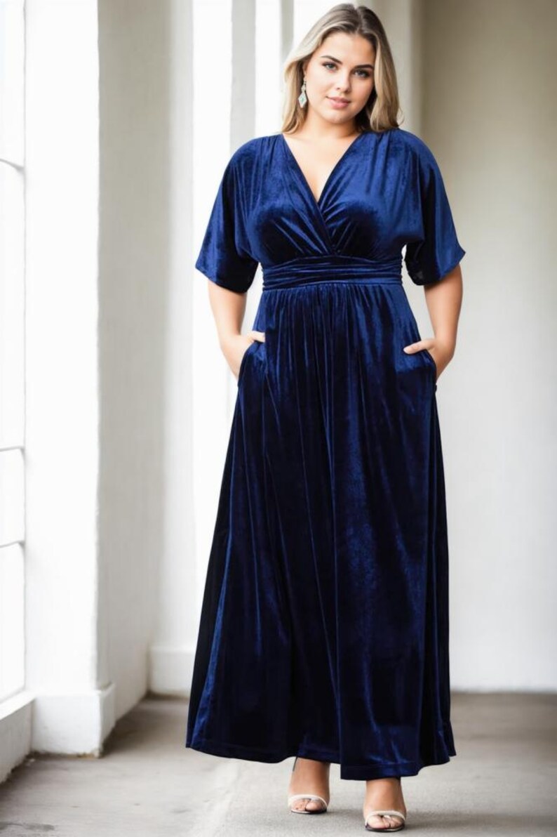 May include: A long, navy blue velvet maxi dress with a V-neckline and short sleeves. The dress has a fitted bodice and a flowing skirt.