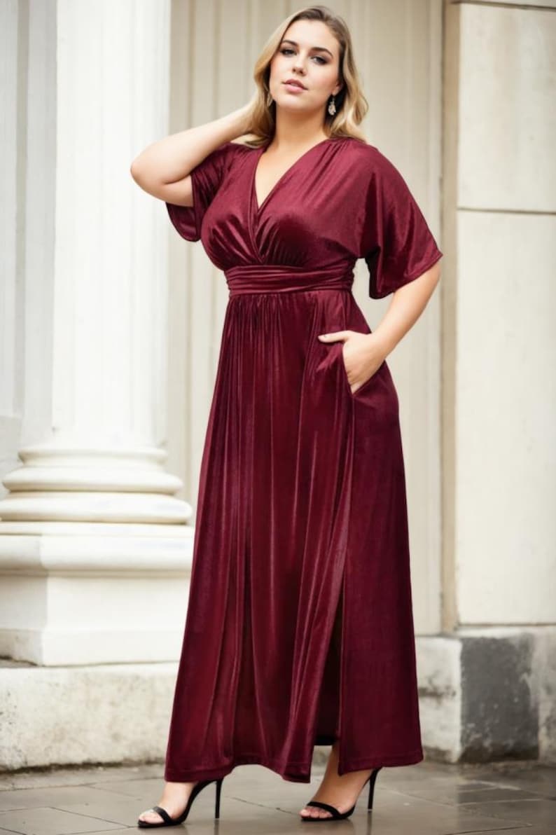 May include: A long, burgundy velvet maxi dress with a V-neckline, short sleeves, and a side slit. The dress has a fitted bodice and a flowing skirt.