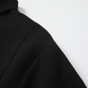 May include: Close-up of the black fabric of a mock neck shirt.