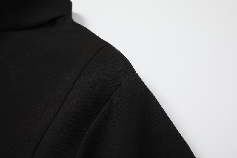 May include: Close-up of the black fabric of a mock neck shirt.
