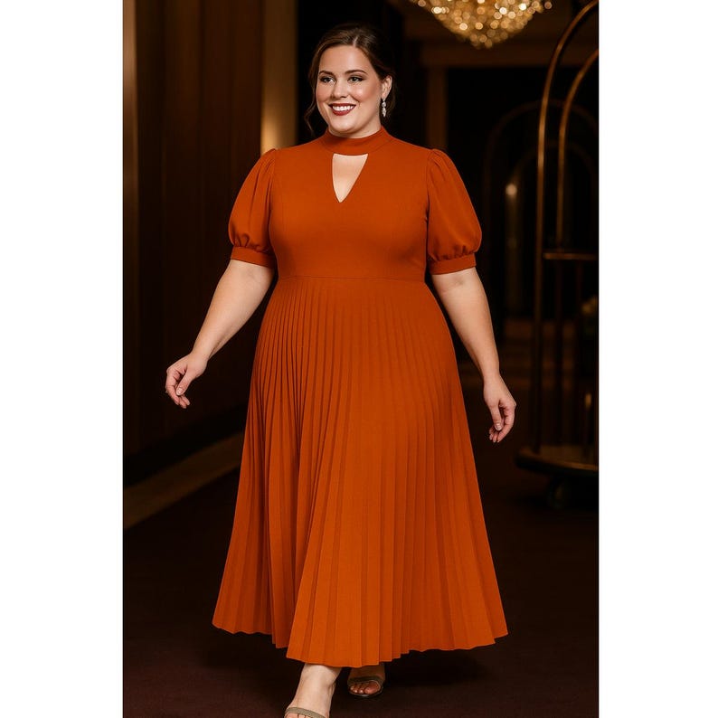 May include: A rust-colored midi dress with a keyhole neckline and pleated skirt. The dress features short, puffed sleeves and a fitted bodice. The model is smiling and walking forward in a well-lit hallway.