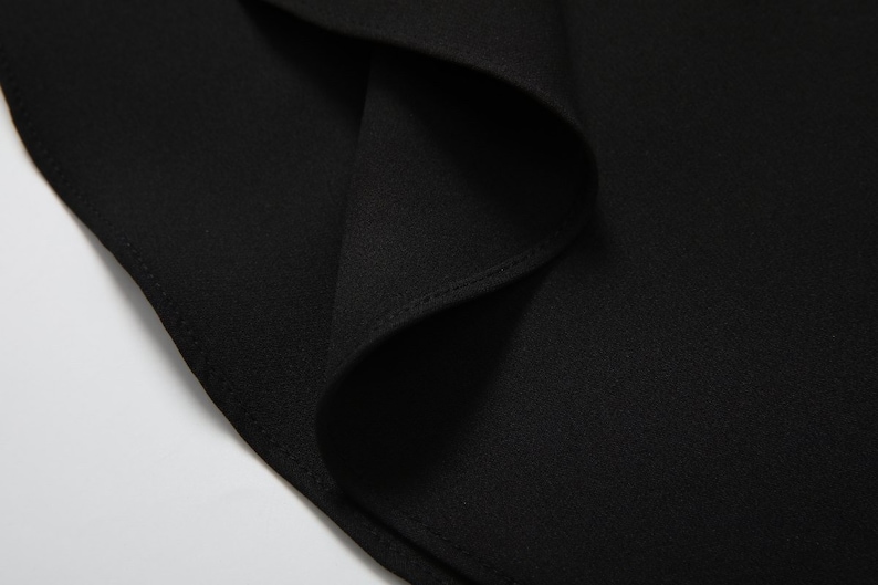 May include: Close-up of black fabric with a subtle texture. The fabric is folded and has a seam along the edge.