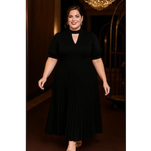 May include: A black midi dress with a keyhole neckline and pleated skirt. The dress features short, puffed sleeves and a fitted bodice. The model is wearing the dress in a well-lit hallway.