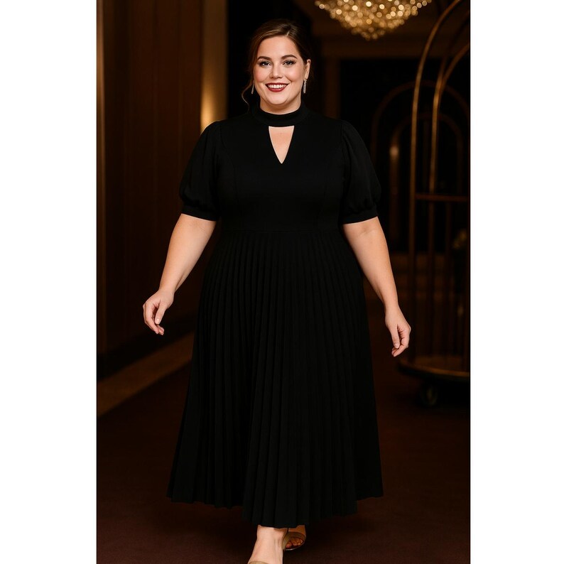 May include: A black midi dress with a keyhole neckline and pleated skirt. The dress features short, puffed sleeves and a fitted bodice. The model is wearing the dress in a well-lit hallway.