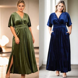 May include: Two women wearing long, velvet maxi dresses. The dress on the left is a dark green colour and the dress on the right is a dark blue colour. Both dresses have a V-neckline, short sleeves, and a fitted waist.