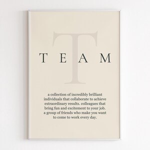 Puede incluir: Un cartel enmarcado con la palabra "TEAM" en una fuente serif, con una gran "T" detrás de la palabra. Debajo de la palabra hay una definición de "TEAM", que describe a un grupo de personas que colaboran para lograr resultados extraordinarios.