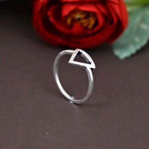 Peut inclure: Une bague en argent avec un design géométrique en forme de triangle. La bague est simple et moderne.