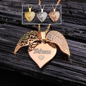 Puede incluir: Un collar con un colgante de corazón de oro con dos alas. Un ala es de filigrana y la otra está engastada con piedras transparentes. El corazón tiene la palabra "Mum" grabada.