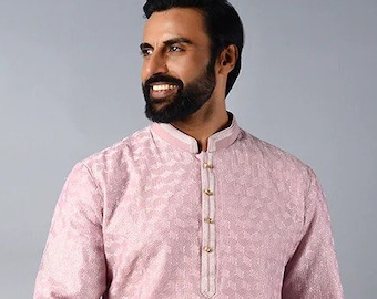 May include: A pink long-sleeved kurta with a button-up collar and a subtle geometric pattern. The kurta is worn with white trousers and brown shoes.