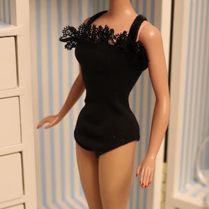 May include: A blonde doll wearing a black lace-trimmed swimsuit with a black headband. The doll is standing on a black and white chequered floor.
