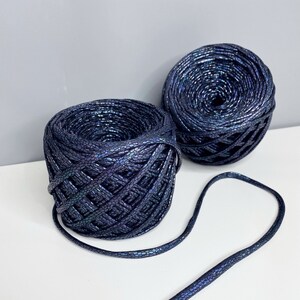 May include: Two spools of dark blue iridescent cord with a textured finish. The cord is lying on a white surface.