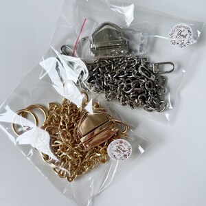 May include: Two sets of gold and silver chain straps with clasps and rings packaged in clear plastic bags. Each bag has a small round sticker with the text "Thank you".