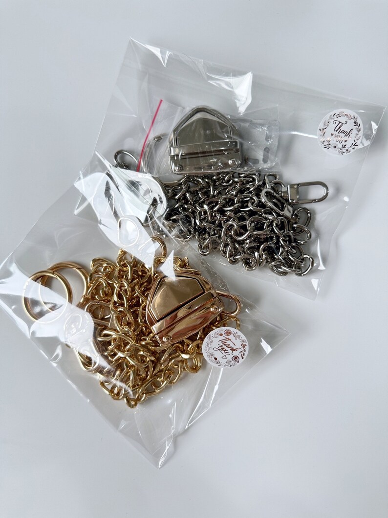 May include: Two sets of gold and silver chain straps with clasps and rings packaged in clear plastic bags. Each bag has a small round sticker with the text "Thank you".