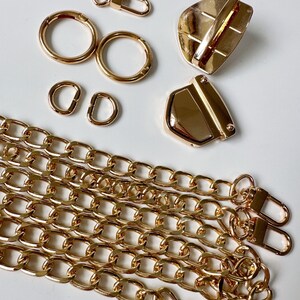 May include: Gold-toned metal hardware for a bag or purse, including two D-rings, two round rings, a swivel clasp, a lobster clasp, and two chain links.