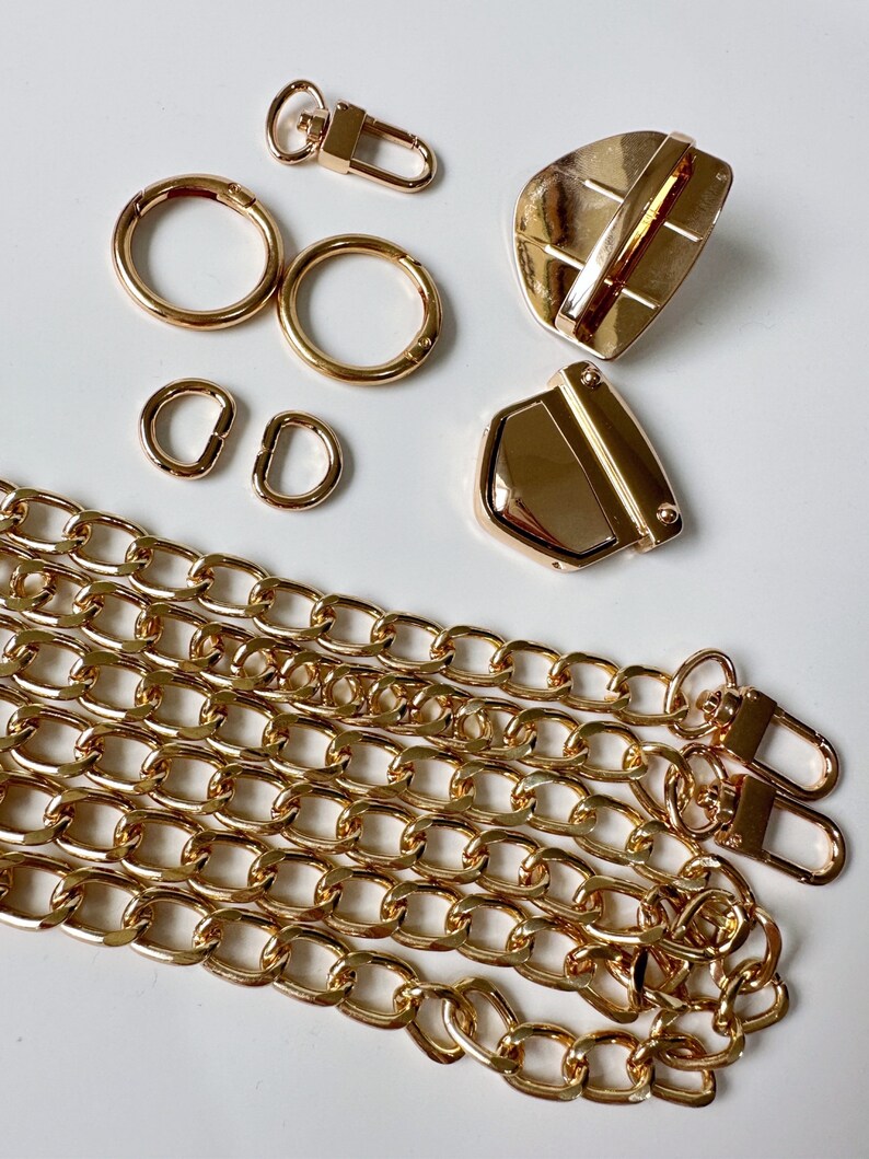 May include: Gold-toned metal hardware for a bag or purse, including two D-rings, two round rings, a swivel clasp, a lobster clasp, and two chain links.