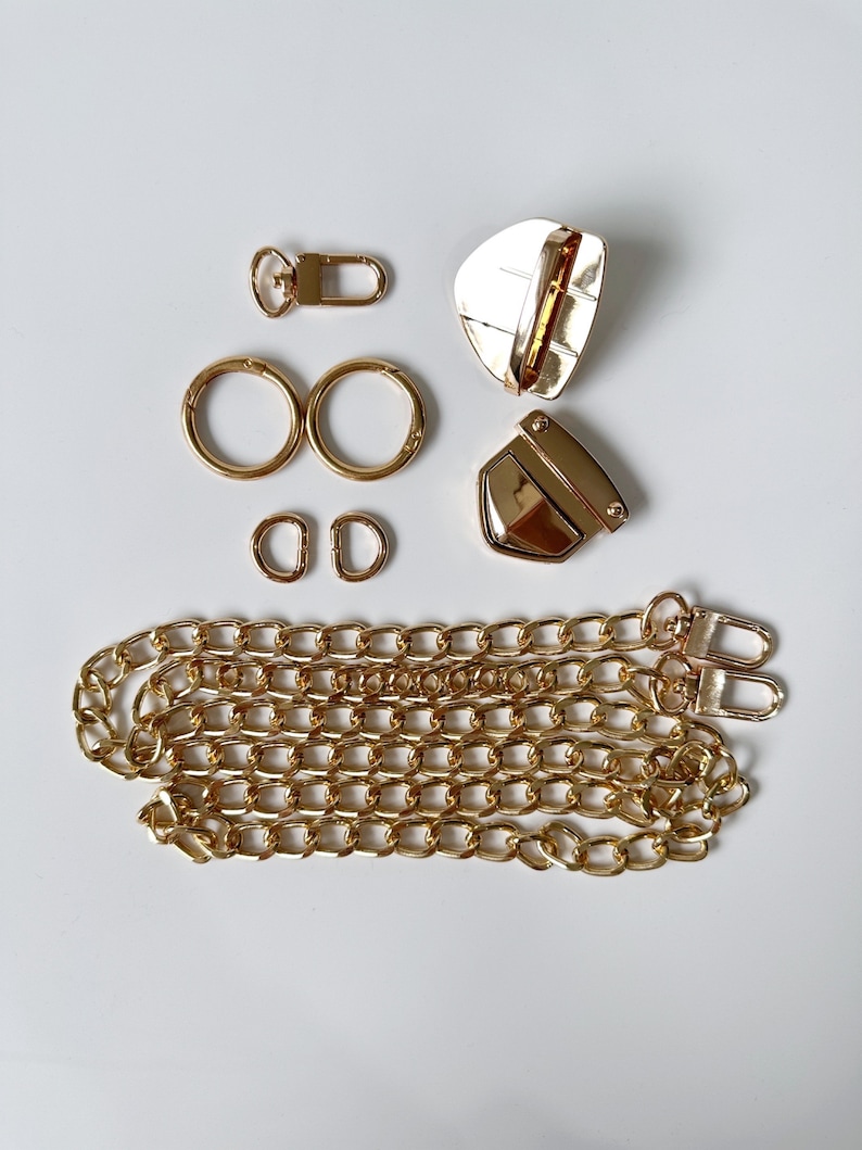 May include: Gold-toned metal hardware set for a bag or purse. The set includes two swivel clasps, two D-rings, two jump rings, a chain, and a lobster clasp.
