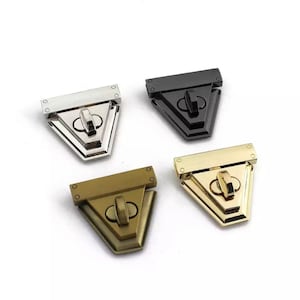 Può includere: Quattro chiusure metalliche in diverse finiture: argento, nero, oro e bronzo. Ogni chiusura ha una forma triangolare con un piccolo pomo rotondo decorativo.