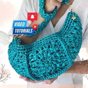 May include: A turquoise crocheted handbag with a curved design and a matching strap. The bag has gold-coloured hardware and a small heart-shaped charm. The words "VIDEO TUTORIALS" are displayed on a blue banner.