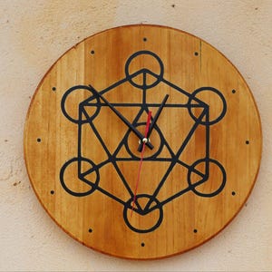 May include: A wooden clock with a geometric design in black on the face. The clock has black hands and a red second hand.