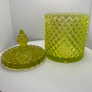 以下が含まれることがあります： 蓋付きの黄色いガラスの瓶。瓶と蓋はダイヤモンド模様です。