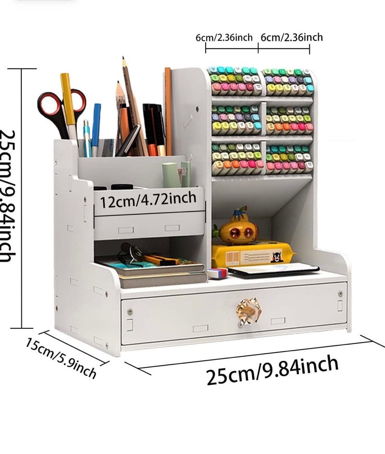 May include: White desktop organizer with a drawer and multiple compartments. The organizer is 9.84 inches wide, 9.84 inches tall, and 5.9 inches deep. It has a small drawer with a decorative knob and a compartment for pens and pencils. There is a larger compartment for markers or other supplies. The organizer is made of wood and has a white finish.